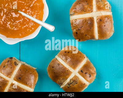 Hot cross bun con confettura di albicocca contro uno sfondo blu Foto Stock