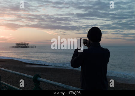 Uomo di fotografare Brighton il Molo Ovest su uno smartphone Foto Stock