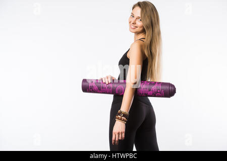 Vista posteriore ritratto di una giovane donna di fitness con materassino yoga su sfondo bianco Foto Stock