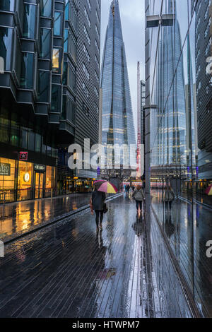 Signora precipitando da con ombrello in caso di pioggia nella città di Londra vista della Shard Foto Stock