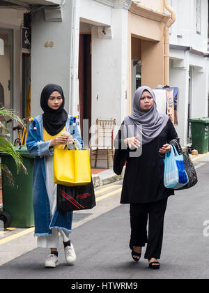 Due donne musulmane il trasporto delle borse della spesa a piedi lungo Haji Lane Singapore. Foto Stock