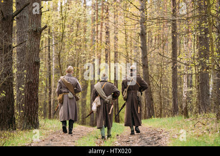 Tre Re-enactors vestito come Soviet russo Rosso esercito di soldati di fanteria della II Guerra Mondiale in marcia lungo la strada forestale a stagione primaverile. Foto Stock