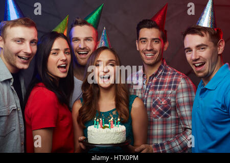 Amici di estatica festeggia il compleanno della ragazza felice Foto Stock
