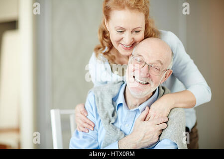 Ritratto di anziani dai capelli grigi uomo abbracciando la moglie e sorridente godendo tranquilla pensione giorni a casa Foto Stock