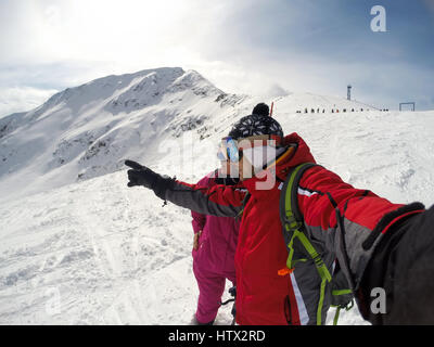 Sciatore mostra a femmina qualcosa in distanza sulla montagna innevata Foto Stock