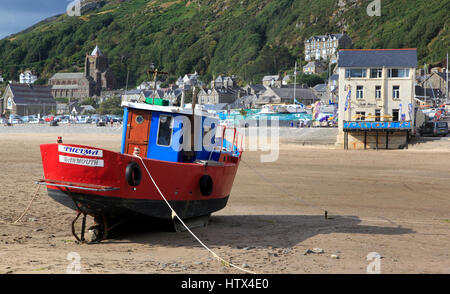 Un barche colorate si siede sul Barmouth Sands con il bulk di dinas Oleu dietro, Barmouth, Galles, Europa Foto Stock