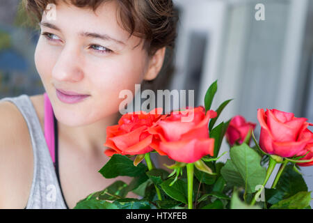 Donna sorridente da red bouquet di rose in vaso Foto Stock