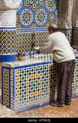 Fes, Marocco. Posizionare Nejjarine. Uomo di ottenere acqua della fontana. Foto Stock