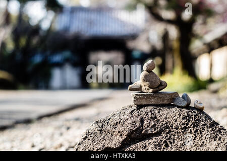 Una pila di ciottoli in condizioni di equilibrio precario di fronte a un santuario giapponese entrata in Giappone. Foto Stock