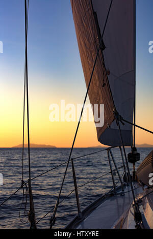 Yacht, vela Jib, rigging e tramonto sul Mar Mediterraneo. Vista da un ponte di una barca a vela, yacht. Sicilia, Italia Foto Stock