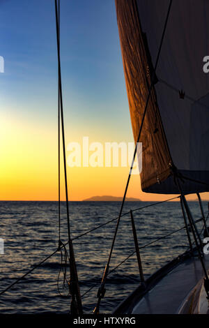 Yacht, vela Jib, rigging e tramonto sul Mar Mediterraneo. Vista da un ponte di una barca a vela, yacht. Sicilia, Italia Foto Stock