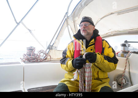 Uomo con la fune mentre è seduto su yacht Foto Stock