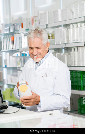 Senior farmacista la scansione di codice a barre della bottiglia di shampoo al bancone Foto Stock