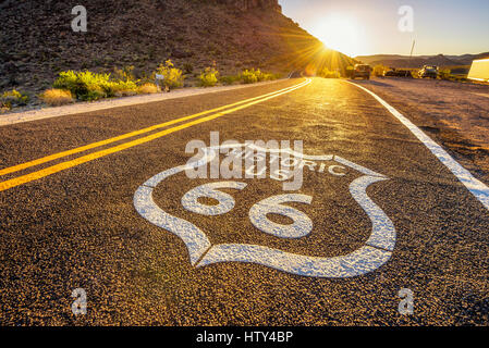 Strada segno sulla storica Route 66 nel deserto di Mojave fotografati contro il sole al tramonto Foto Stock