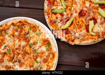 Pizza sul legno scuro del tavolo con ingredienti freschi Foto Stock