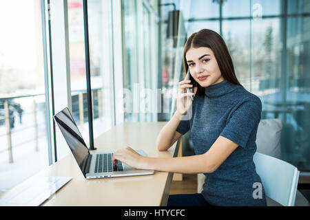 Vista laterale Ritratto di giovane imprenditrice avente attività chiamata in ufficio. Donna che parla al telefono cellulare in ufficio Foto Stock