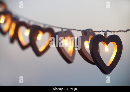 A forma di cuore le luci della stringa appeso a una fila Foto Stock