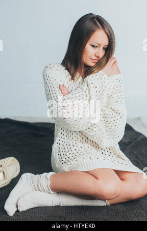 Donna in maglia maglione seduta su di un letto Foto Stock