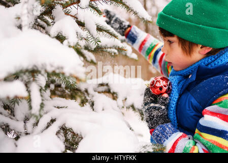 Ragazzo decorare un albero di Natale in giardino Foto Stock