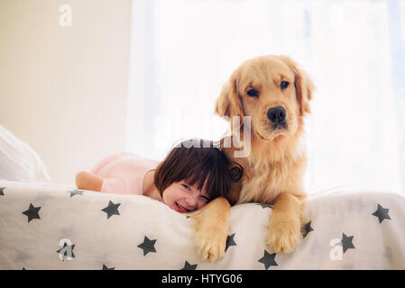 Ragazza distesa sul letto con il golden retriever cane Foto Stock