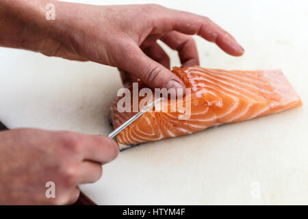 Close up di chef è la rimozione di osso di pesce dal salmone Foto Stock