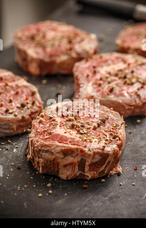 Carne cruda bistecca su sfondo scuro pronto per l'arrosto Foto Stock