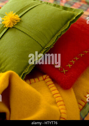 Close-up di coloratissimi cuscini di feltro con una decorazione a croce e coperta stitch Foto Stock