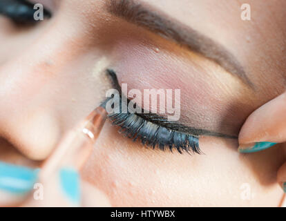 Primo piano dettaglio della palpebra womans e applicazione di ciglia trucco eyeliner Foto Stock