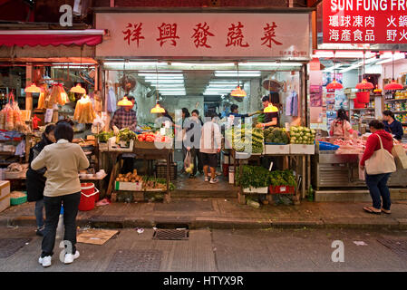 La popolazione locale acquisto di frutta fresca, verdura, pesce e carne da uno dei negozi a Wan Chai mercato umido, Hong Kong. Foto Stock