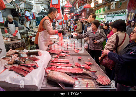 Asiatiche locali popolo cinese acquisto di pesce fresco da uno dei negozi a Wan Chai mercato umido, Hong Kong. Foto Stock