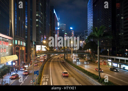 Una vista dei grattacieli e il traffico con motion blur lungo Gloucester Road sull isola di Hong Kong nella sera notte tempo. Foto Stock