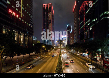 Una vista dei grattacieli e il traffico con motion blur lungo Gloucester Road sull isola di Hong Kong nella sera notte tempo. Foto Stock