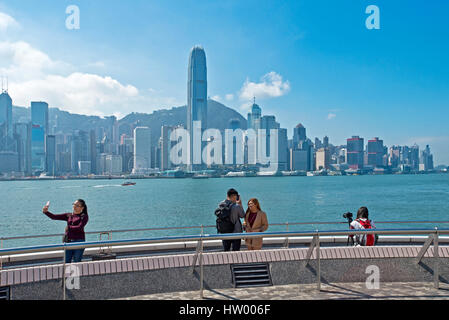 I turisti fotografare le fotografie dal Kowloon Public Pier di grattacieli lungo l'Isola di Hong Kong. Foto Stock