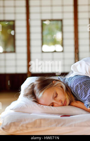 La donna caucasica indossare uno yukata in casa tradizionale giapponese futon Foto Stock