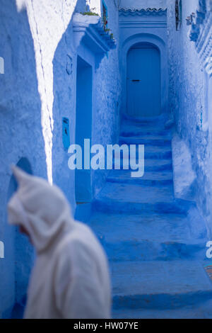 Uomo con un abito tradizionale sta camminando nel blu medina di Chefchaouen, Marocco. Foto Stock