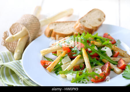 Insalata mista con fried asparagi bianchi, greco il formaggio feta, rucola e pomodori ciliegini, servita con baguette Foto Stock