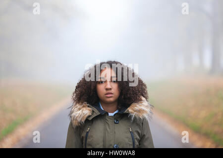 Outdoor ritratto della splendida razza mista americano africano ragazza adolescente di sesso femminile al di fuori del bambino in un parco su nebbioso giorno Foto Stock