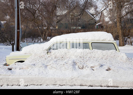 Auto congelato sotto un sacco di neve è completamente bloccato sul lato della strada durante una tempesta di neve nella curvatura Oregon. Foto Stock