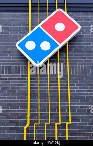 Domino's Pizza logo in nero di un muro di mattoni, giallo tubi di utilità nel retro di un ristorante a Londra, Ontario, Canada. Foto Stock