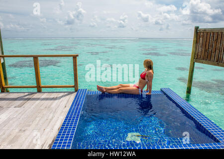 Maldive Rangali Island. Conrad Hilton Resort. Donna rilassante nell'oceano villa piscina che si affaccia sull'oceano. (MR) Foto Stock