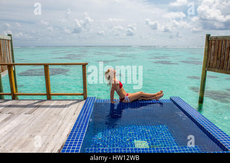 Maldive Rangali Island. Conrad Hilton Resort. Donna rilassante nell'oceano villa piscina che si affaccia sull'oceano. (MR) Foto Stock