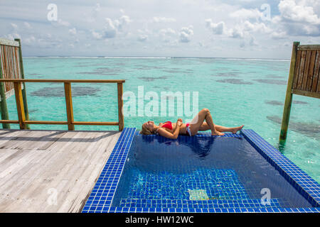 Maldive Rangali Island. Conrad Hilton Resort. Donna rilassante nell'oceano villa piscina che si affaccia sull'oceano. (MR) Foto Stock