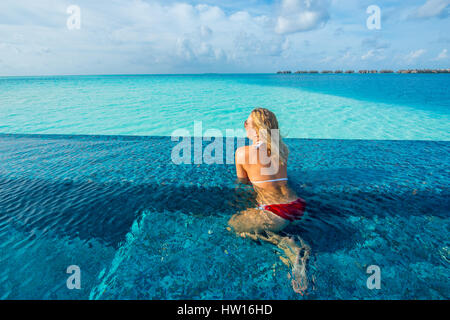 Maldive Rangali Island. Conrad Hilton Resort. La donna in una piscina infinity sull'oceano. (MR) Foto Stock