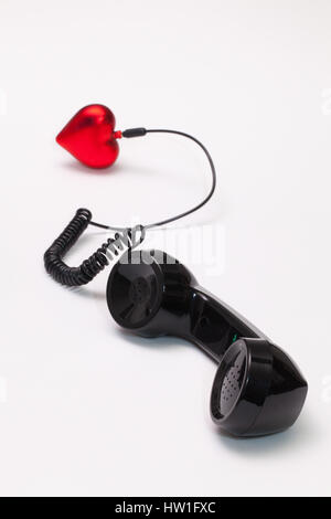 Vecchio ricevitore telefonico e cavo collegamento con cuore rosso. Amore concetto hotline. Foto Stock