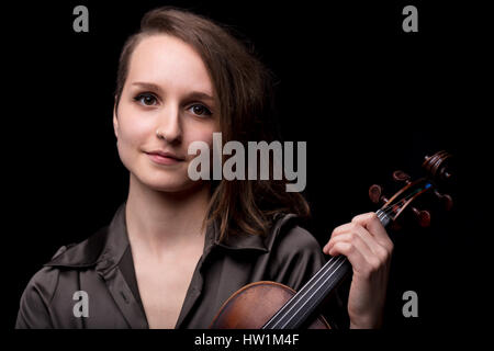 Ritratto di una giovane donna violinits tenendo il suo violino paletta con un leggero sorriso, il concetto di musica classica Foto Stock