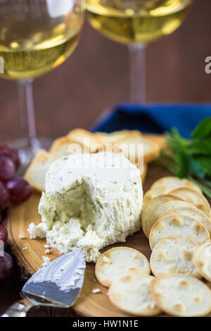 Soft aromatizzato il formaggio cremoso con aglio ed erbe fini su un pannello di legno con cracker. Foto Stock