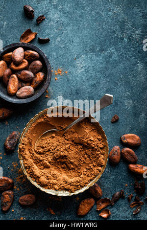 Cacao in polvere e chicchi di cacao su sfondo scuro, vista dall'alto Foto Stock