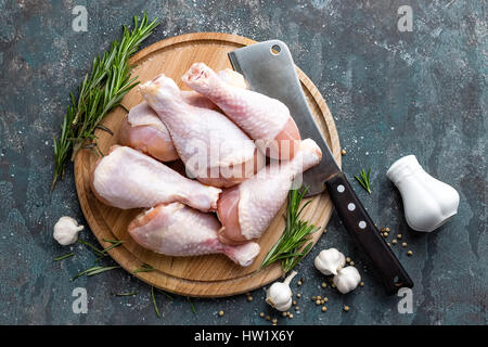 Materie non cotti le cosce di pollo, bacchette sulla tavola di legno, la carne con gli ingredienti per cucinare, vista dall'alto Foto Stock