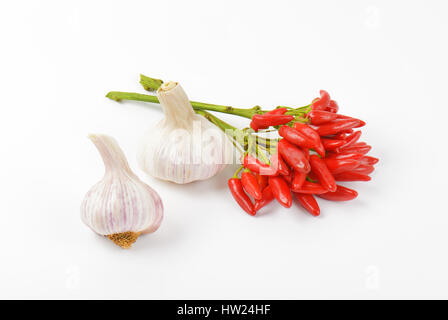 Mazzetto di piccolo peperoncino rosso e bulbi di aglio su sfondo bianco Foto Stock