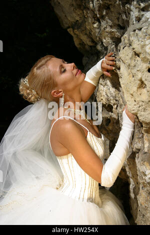 La bella sposa la bionda vicino ad una pietra Foto Stock